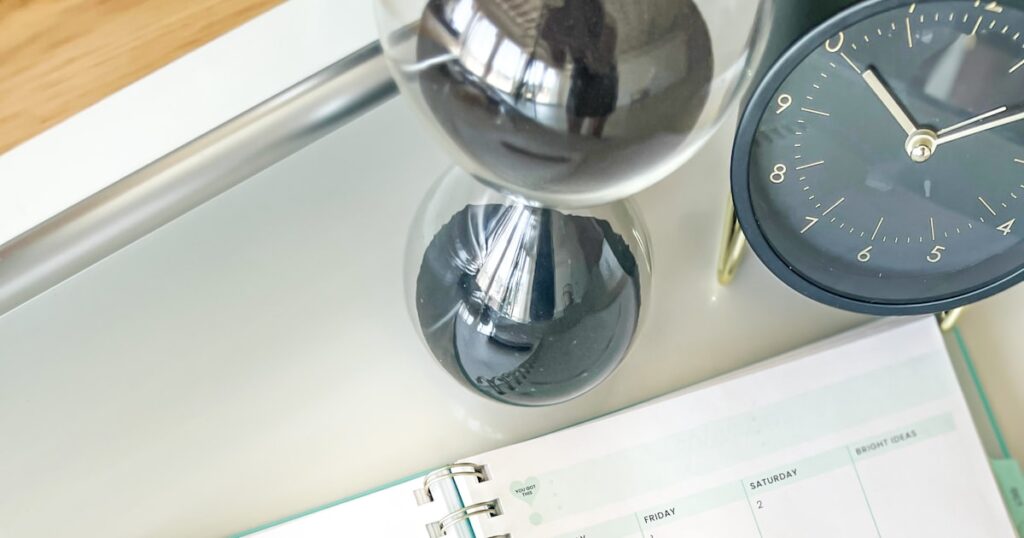 An hourglass, clock and planner on a desk, illustrating how long a personal injury claim takes