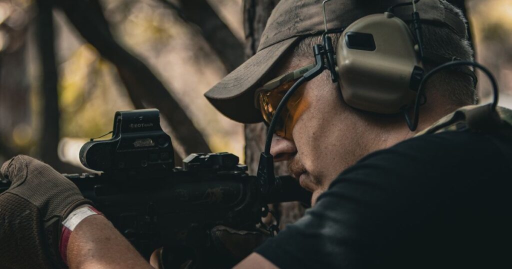 A serviceperson wearing ear defenders on a firing range, illustrating military hearing loss claims